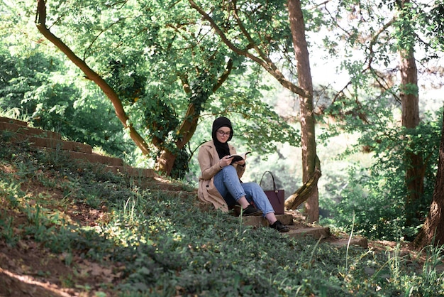 Young muslim girl reading in a park