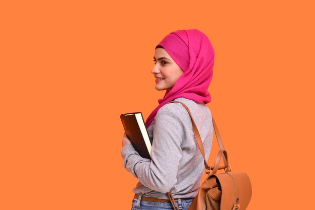 Foto giovane ragazza musulmana che indossa l'hijab borsa appesa e tiene in mano un libro indiano modello pakistano