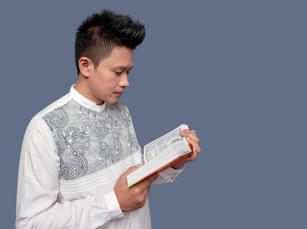 Young muslim man holding and reading Al Quran