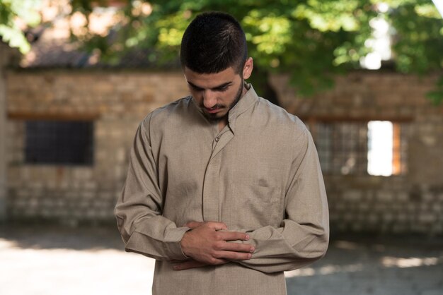 Young Muslim Man Making Traditional Prayer To God While Wearing A Traditional Cap Dishdasha