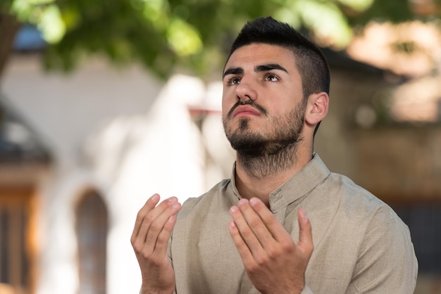 Young Muslim Man Making Traditional Prayer To God While Wearing A Traditional Cap Dishdasha