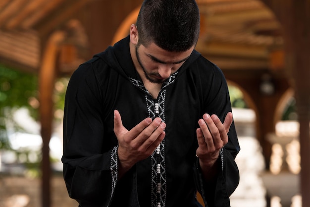 Young Muslim Man Making Traditional Prayer To God While Wearing A Traditional Cap Dishdasha