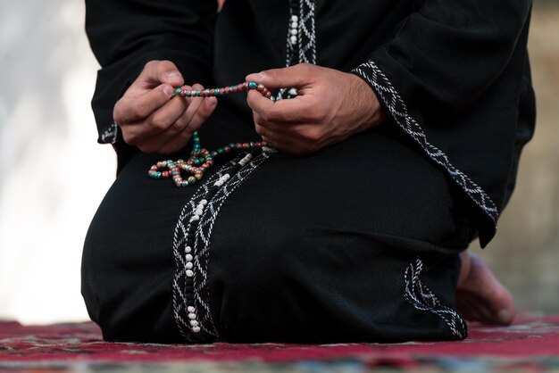 Young Muslim Man Making Traditional Prayer To God While Wearing A Traditional Cap Dishdasha