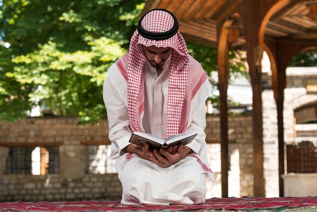 Young Muslim Man Making Traditional Prayer To God While Wearing A Traditional Cap Dishdasha