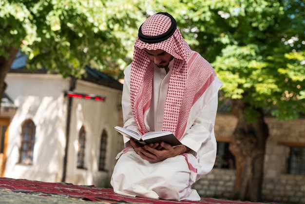 Young Muslim Man Making Traditional Prayer To God While Wearing A Traditional Cap Dishdasha