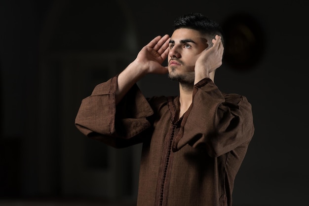 Young Muslim Man Making Traditional Prayer To God While Wearing A Traditional Cap Djellaba