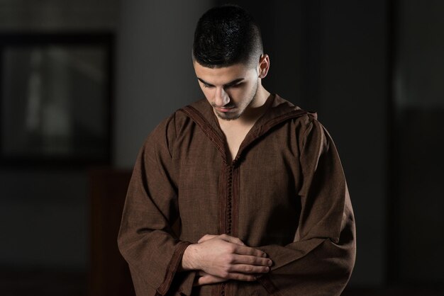 Young Muslim Man Making Traditional Prayer To God While Wearing A Traditional Cap Djellaba