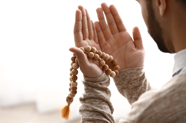 Young Muslim man praying indoors