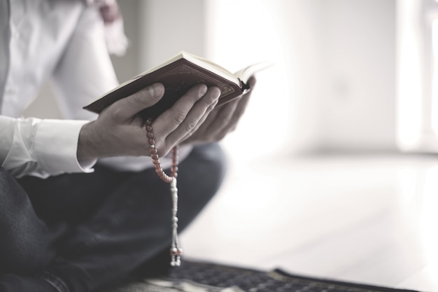 Photo young muslim man reading koran, indoors