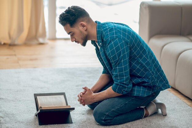 Young muslim praying at home and reading Quran