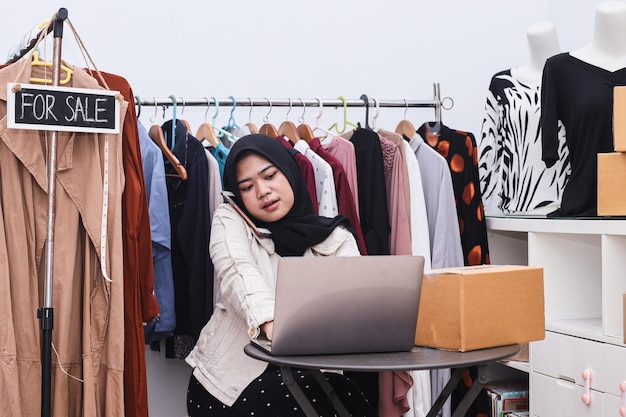 Young muslim woman entrepreneur receiving phone call for new sales order among box of product with l