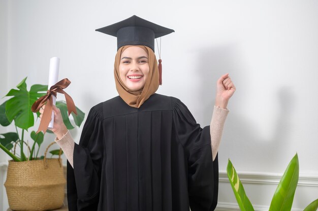 Photo a young muslim woman graduated holding a certification.