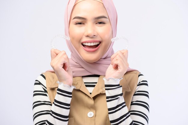 A young muslim woman holding invisalign braces in studio dental healthcare and Orthodontic concept