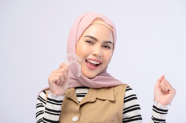 A young muslim woman holding invisalign braces in studio dental healthcare and Orthodontic concept