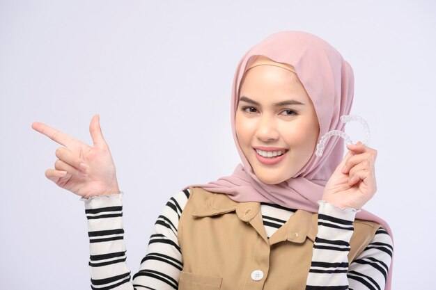 A young muslim woman holding invisalign braces in studio dental healthcare and Orthodontic concept