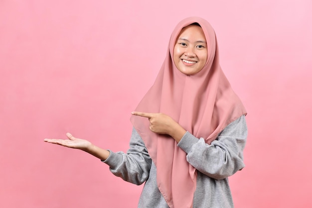 Photo young muslim woman posing excited holding a copy space on palm