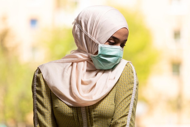 Young Muslim Woman Praying in Mosque With Surgical Mask and Gloves