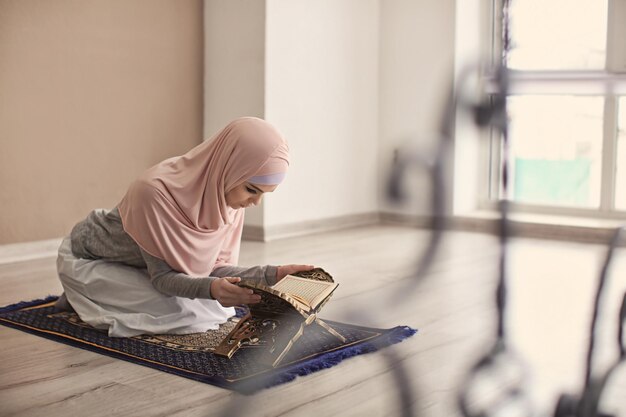 Photo young muslim woman reading koran indoors