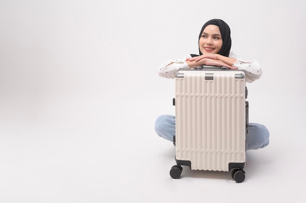 Молодая туристка-мусульманка с багажом на белом фоне