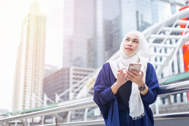 Young muslim woman using smartphone. Looking to sky