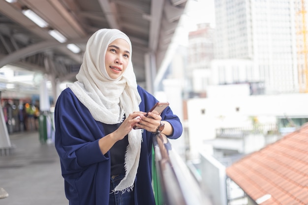 Skytrain 역에 전화를 사용 하여 젊은 무슬림 여성.