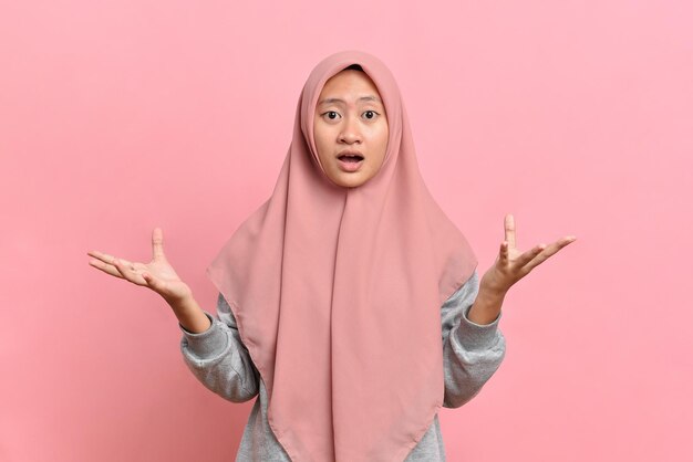 Photo young muslim woman wearing a sweater clueless and confused expression with arms and hands raised