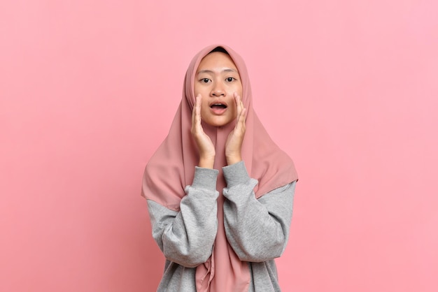 Young Muslim woman with gray sweater shouting with mouth open