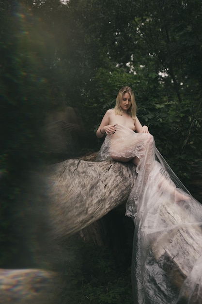 Young naked woman sitting on rock in forest