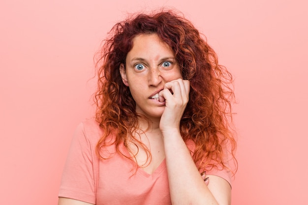 Foto giovane donna rossa naturale e autentica che morde le unghie, nervosa e molto ansiosa.