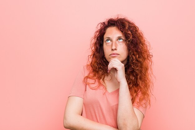 Foto giovane donna rossa naturale e autentica guardando lateralmente con espressione dubbiosa e scettica.