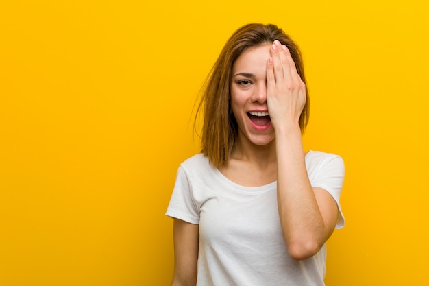 Young natural caucasian woman having fun covering half of face with palm.