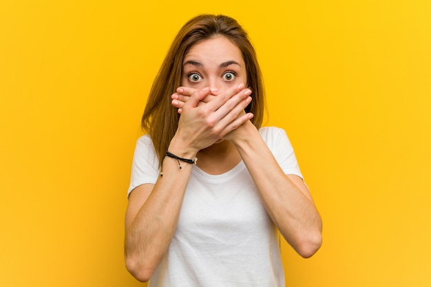 Young natural caucasian woman shocked covering mouth with hands.