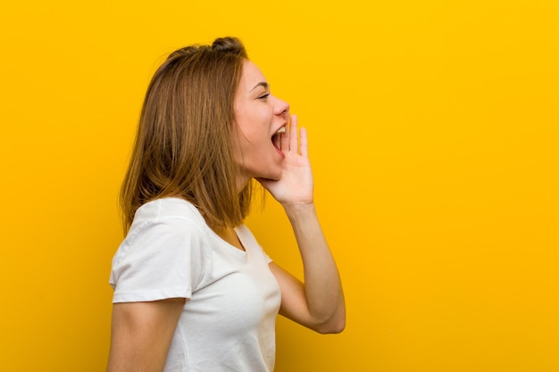 Young natural caucasian woman shouting and holding palm near opened mouth.