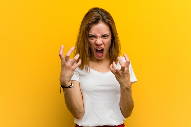 Young natural caucasian woman upset screaming with tense hands.