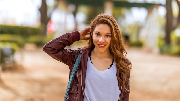 Young natural girl styling her hair in casual dress in the park