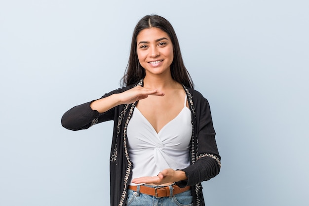 Young natural and pretty arab woman holding something with both hands, product presentation.