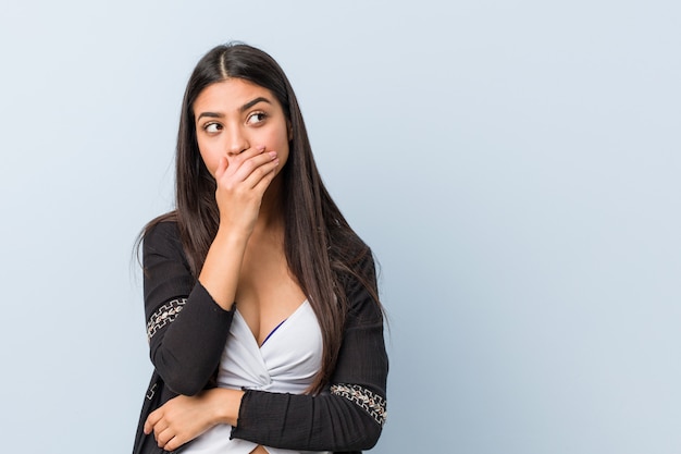 Young natural and pretty arab woman thoughtful looking to a blank space covering mouth with hand.