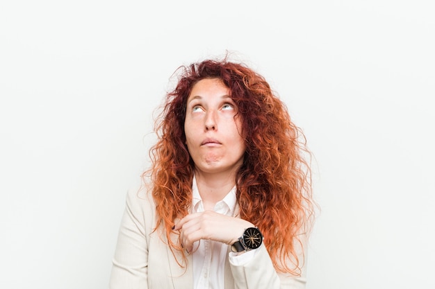 Young natural redhead business woman isolated against white background tired of a repetitive task.