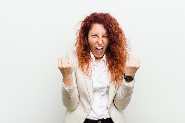 Young natural redhead business woman isolated against white cheering carefree and excited. Victory concept.