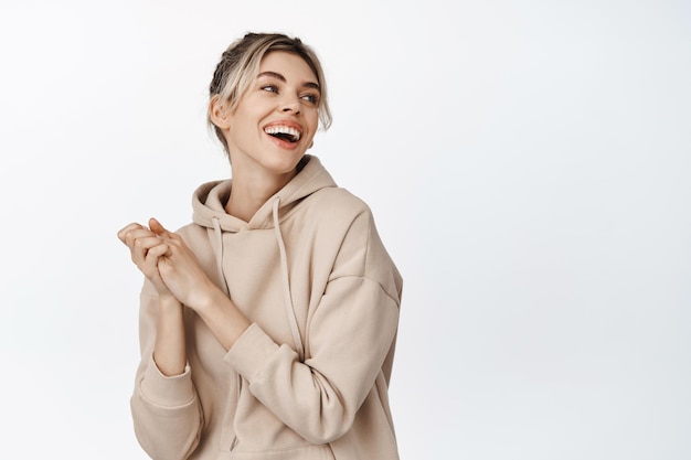 Young natural woman laughing smiling and looking aside girl has nude makeup clean healthy skin stands against white background