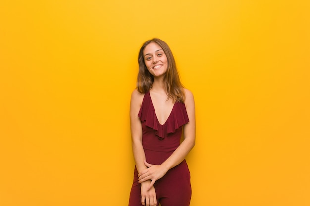 Young natural woman wearing a red dress against an orange wall