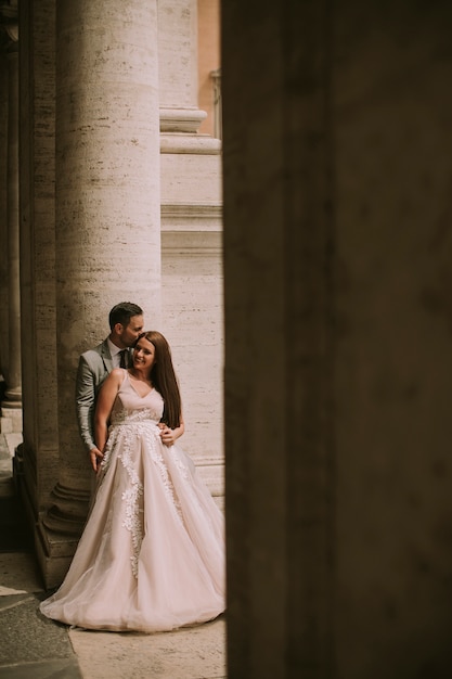 Young newly married couple  posing in Rome with beautiful and ancient architecture in the background