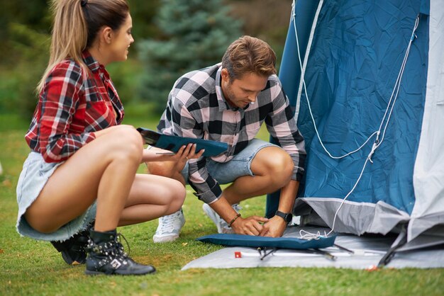 Young nice couple having fun on camping setting up tent. High quality photo