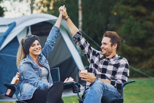 Young nice couple sitting on chairs inf front of tent on camping. High quality photo