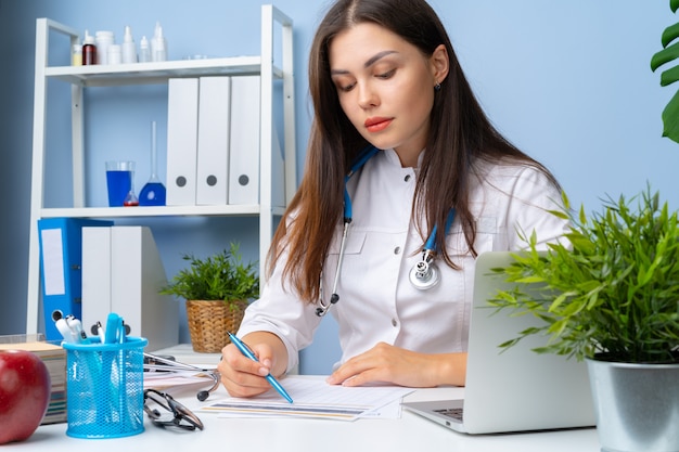 Young nice female doctor working in her office 