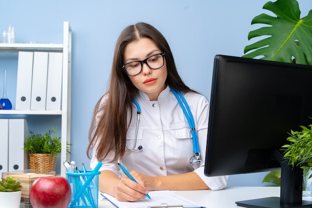 Young nice female doctor working in her office