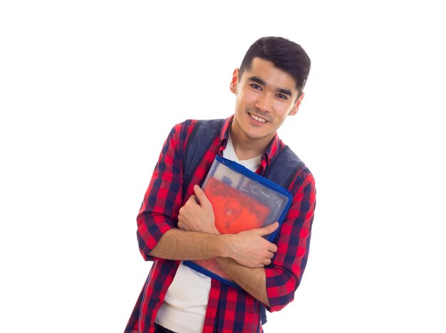 Young nice man in red checkered shirt with blue backpack and folder with copybooks