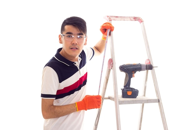 Young nice man with black hair in white and blue tshirt and jeans with orange gloves and protective