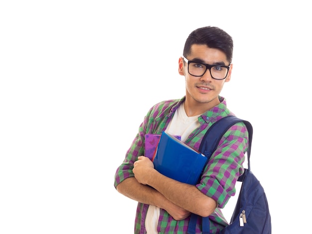 Young nice man with black hair in white Tshirt and checkered shirt with blue backpack holding books