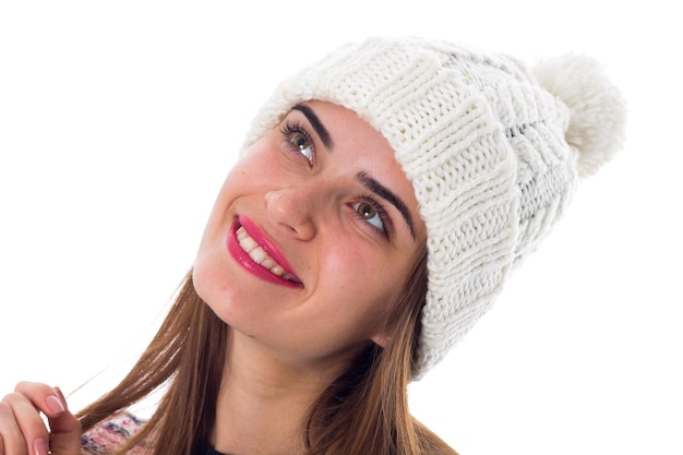 Young nice woman in hat and purple sweater touching hair on white background in studio